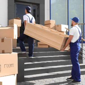 Male movers carrying shelving unit into new house